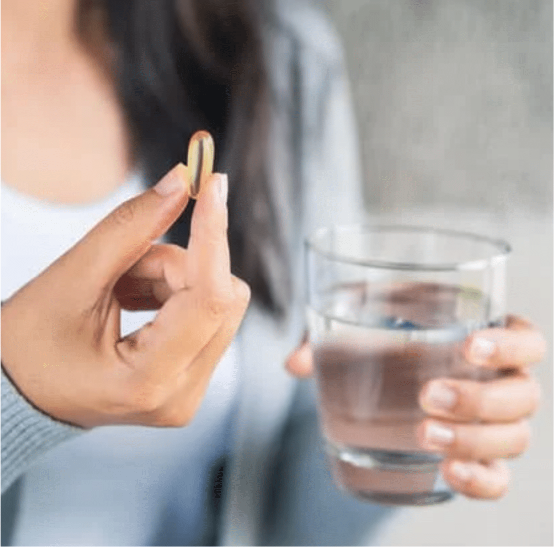woman taking vitamin supplement with water